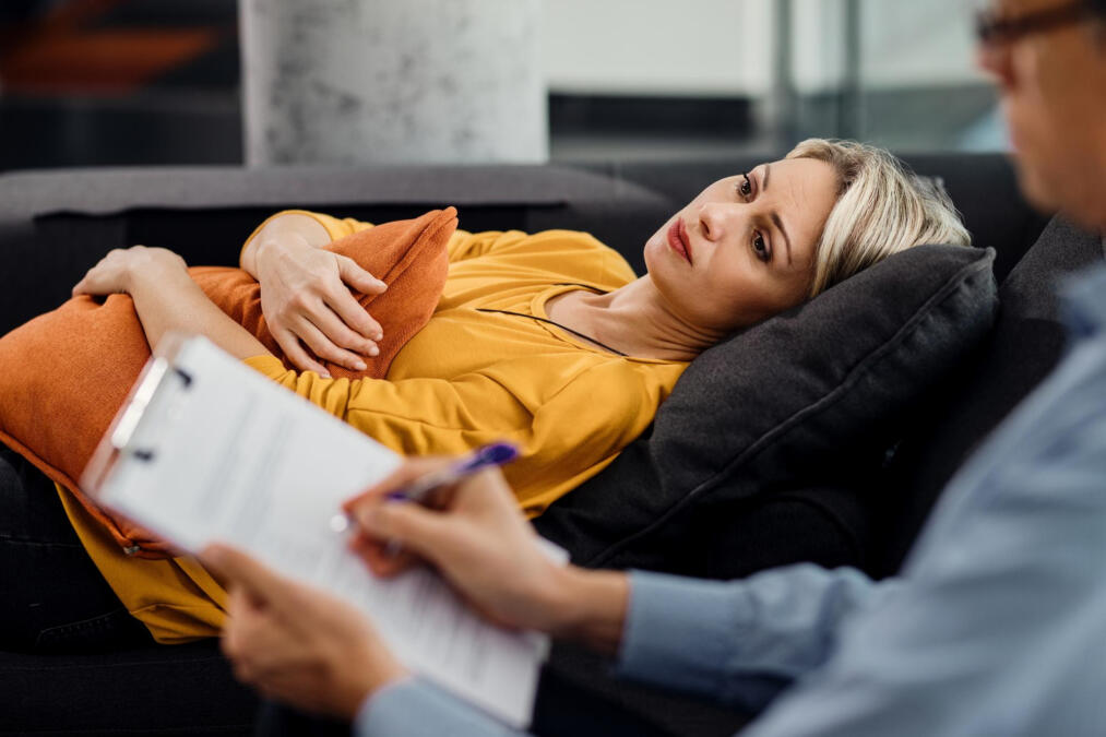 thoughtful woman lying down on psychiatrist s couch during an appointment with her therapist